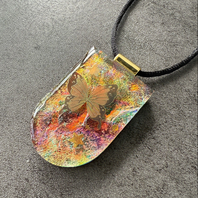 Colorful pendant with butterfly design on a gray surface
