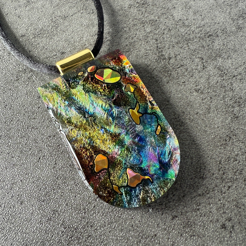 Colorful pendant with gold accents on a gray surface