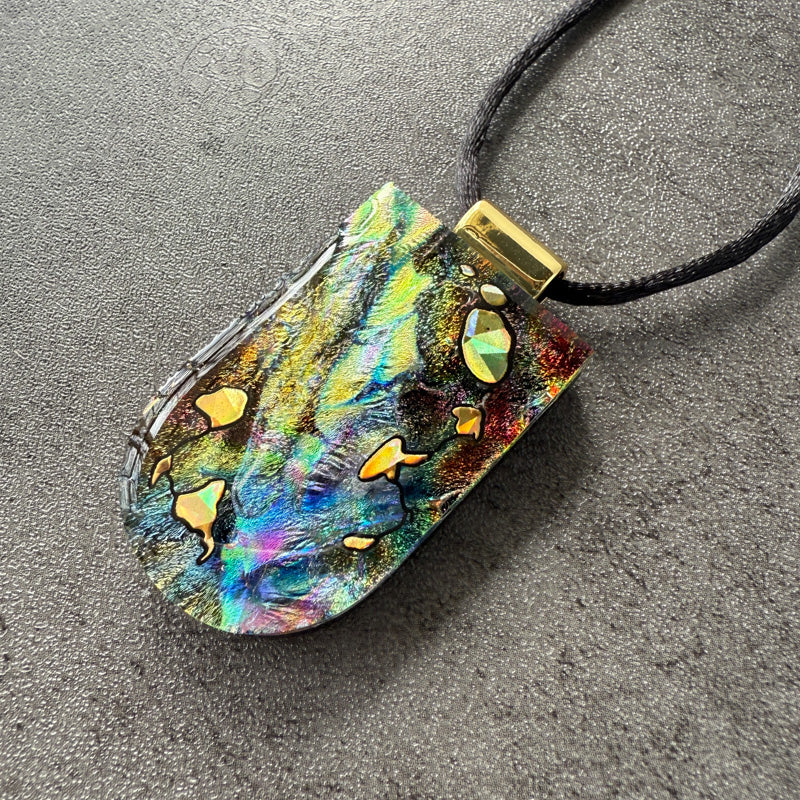 Multicolored pendant with gold accents on a dark surface