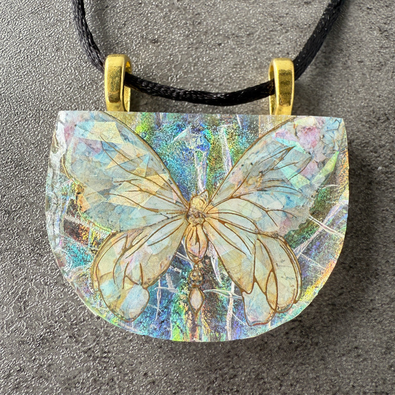 Butterfly pendant on a black cord against a gray background