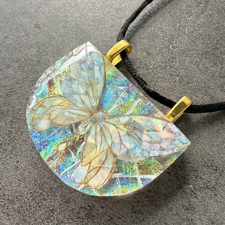 Butterfly pendant on a black cord against a gray background