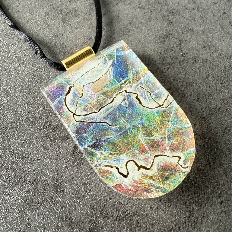 Colorful pendant with a gold accent on a gray surface