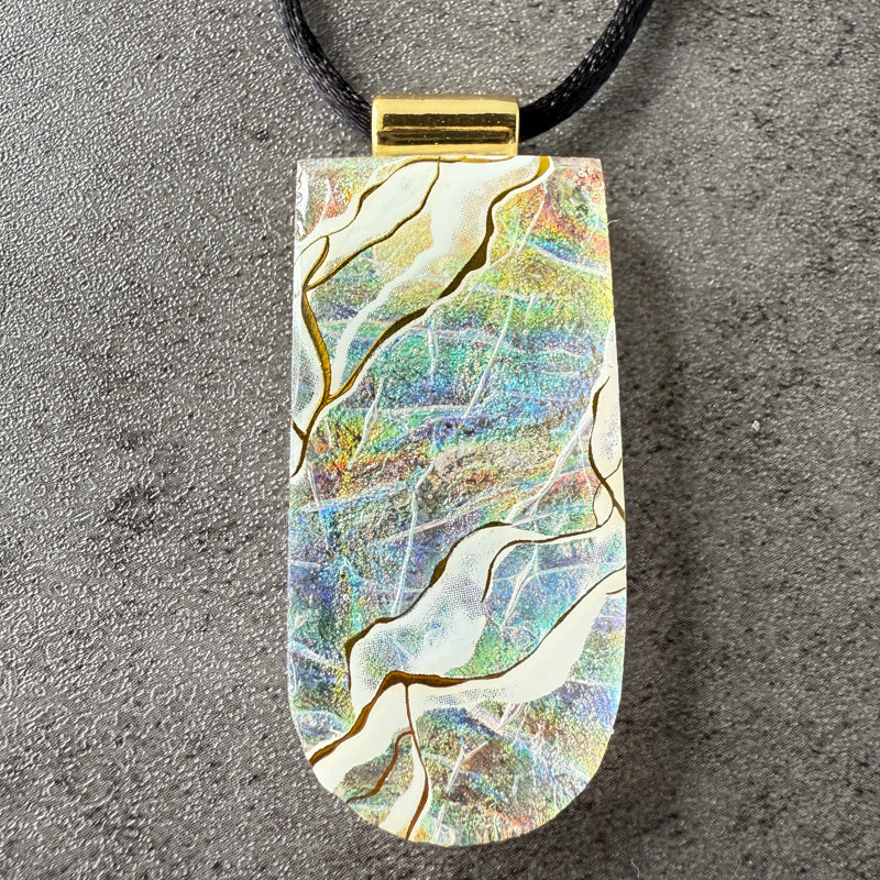 Colorful pendant with gold accents on a gray surface