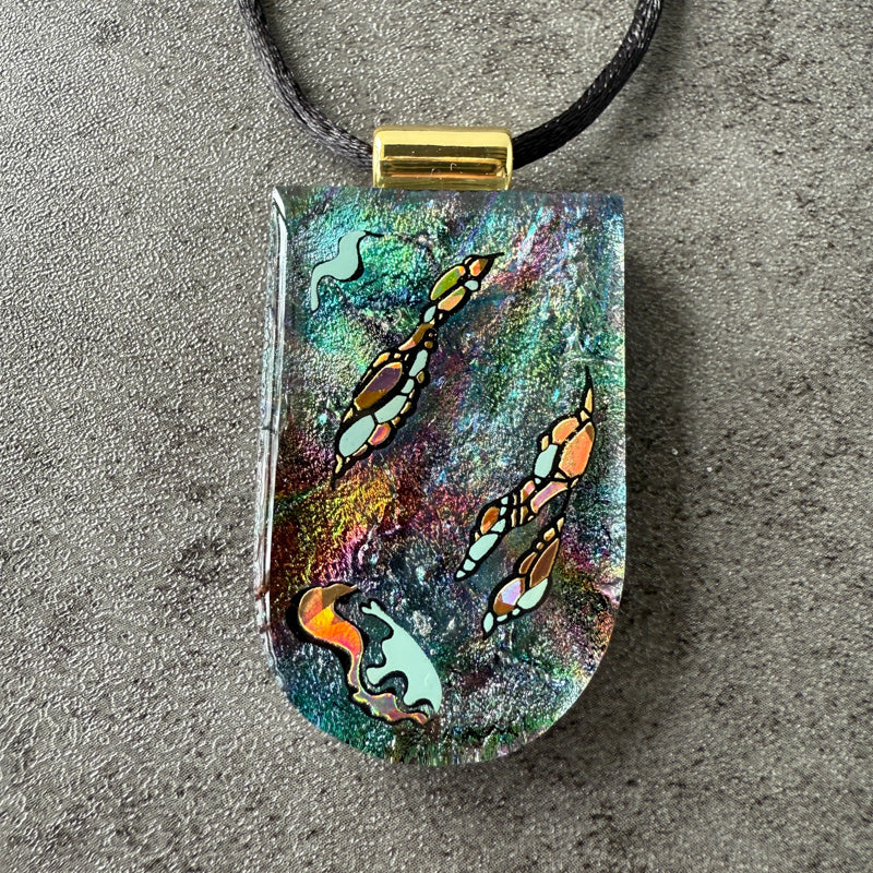 Colorful pendant with abstract designs on a gray surface