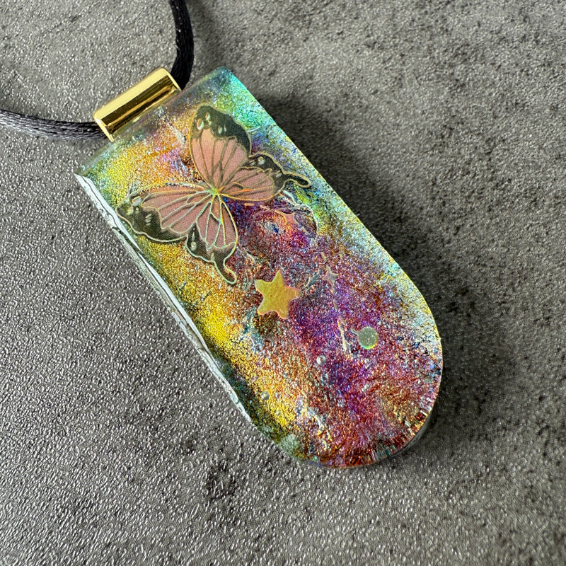 Colorful pendant with butterfly design on a textured surface