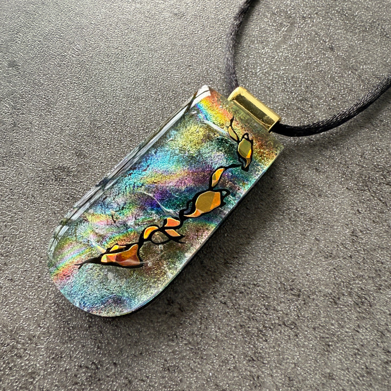 Colorful pendant with abstract designs on a gray surface