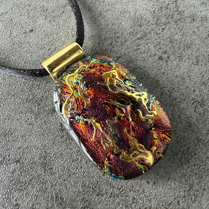 Multicolored pendant with gold accents on a gray surface