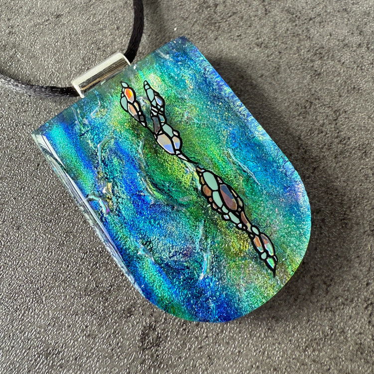 Colorful pendant with artistic design on a textured surface