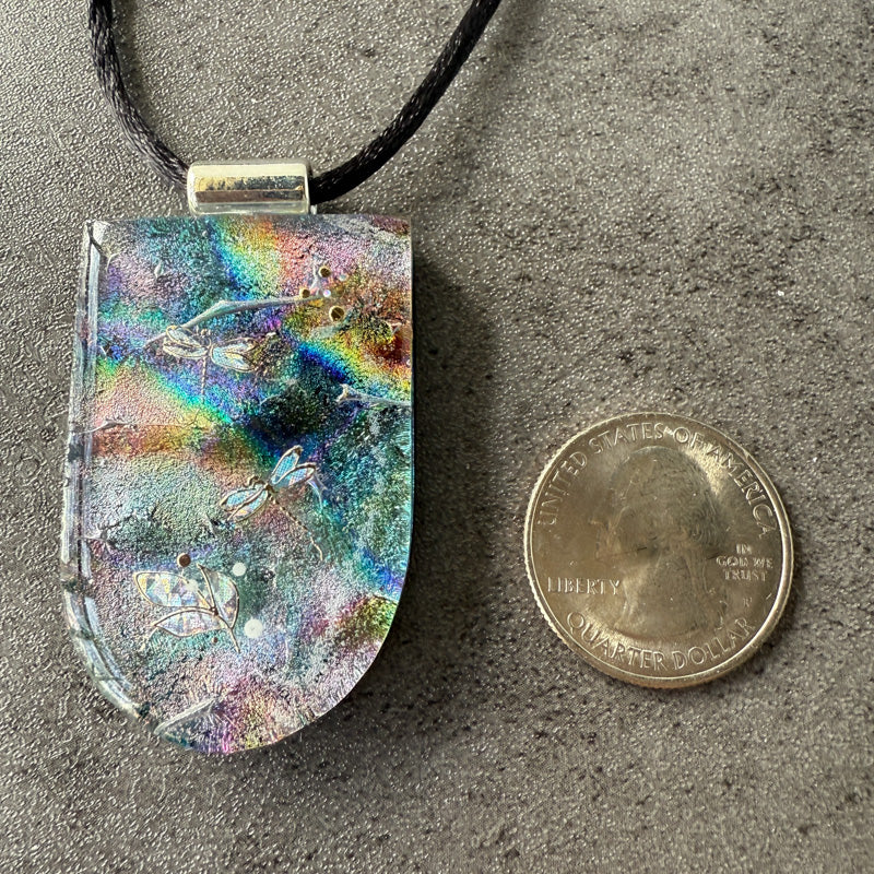 Colorful pendant next to a quarter on a gray surface