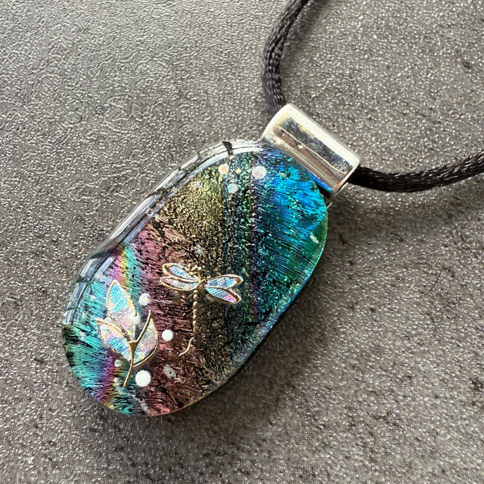 Multicolored pendant on a black cord against a gray background