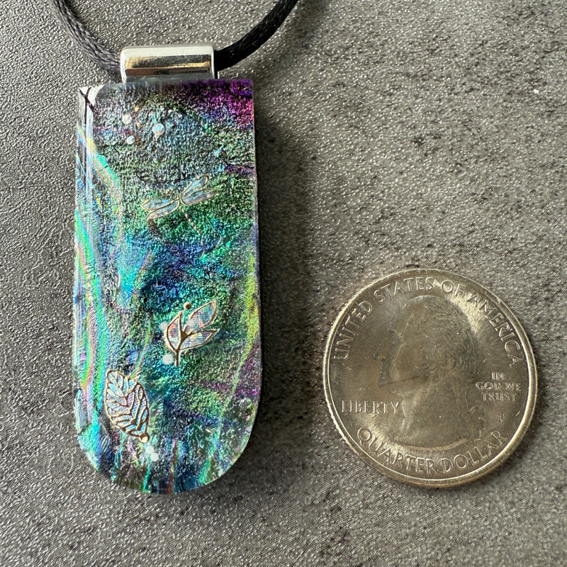 Colorful pendant next to a quarter on a gray surface