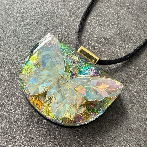 Butterfly-shaped pendant on a black cord against a gray background