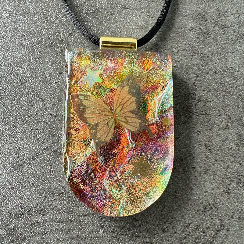 Colorful pendant with a butterfly design on a gray surface