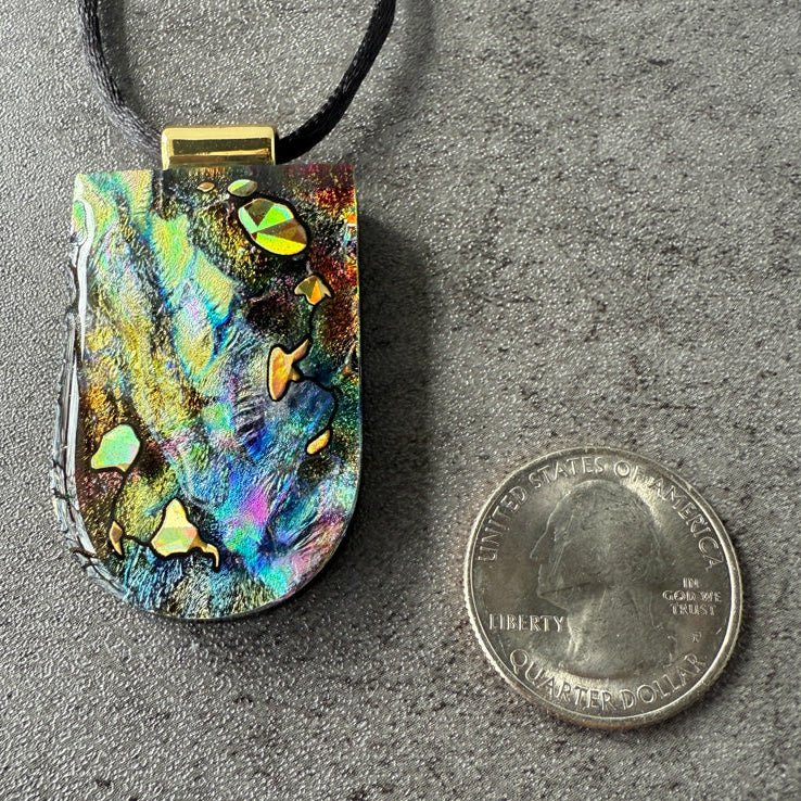 Colorful pendant next to a quarter on a gray surface