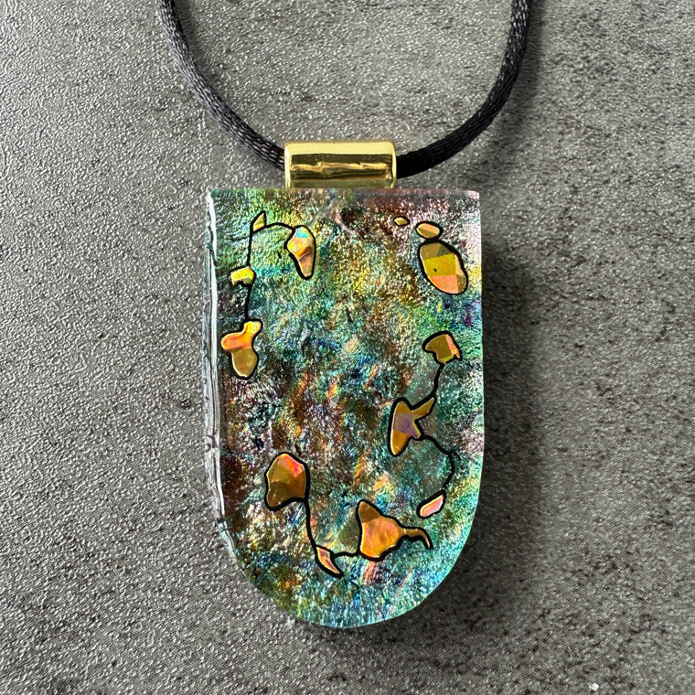 Colorful pendant on a black cord against a gray background