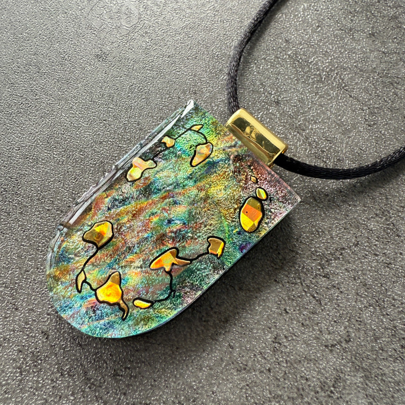 Colorful pendant with abstract designs on a textured surface