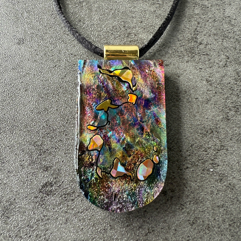 Multicolored pendant with fish design on a gray surface