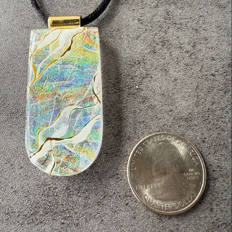 Multicolored pendant on a gray surface with a quarter for scale