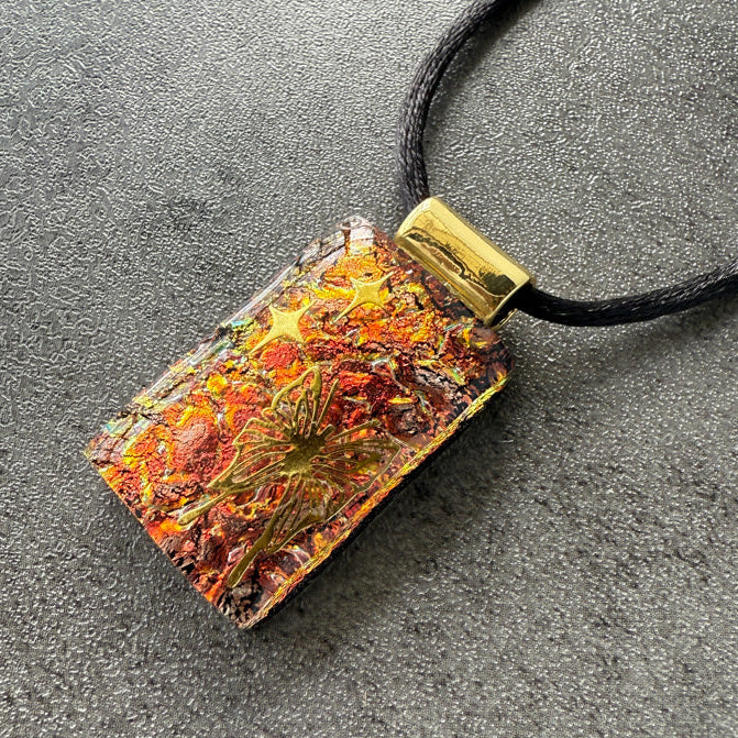 Necklace with a rectangular pendant featuring natural elements on a dark surface