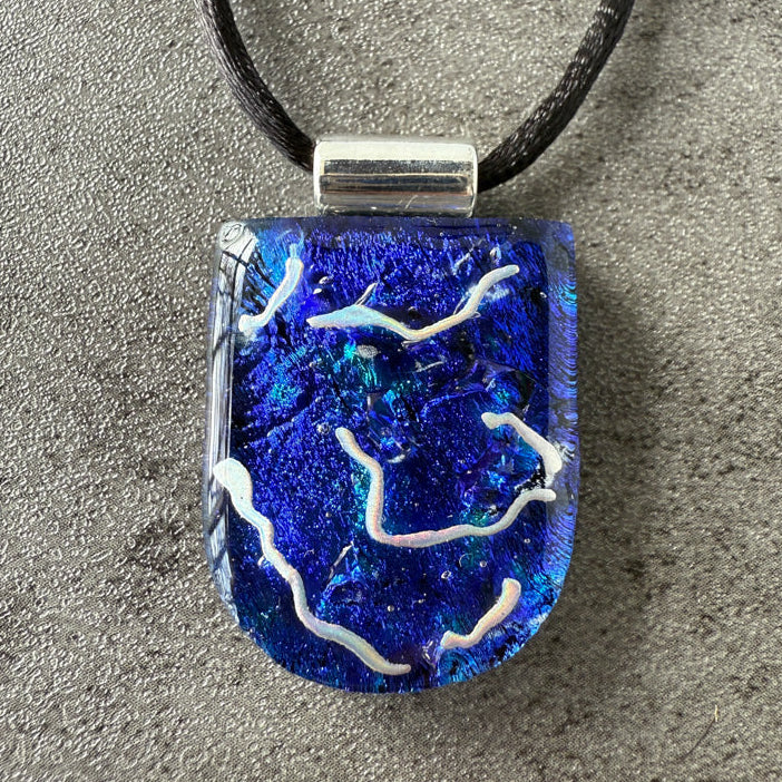 Blue and white pendant on a gray surface