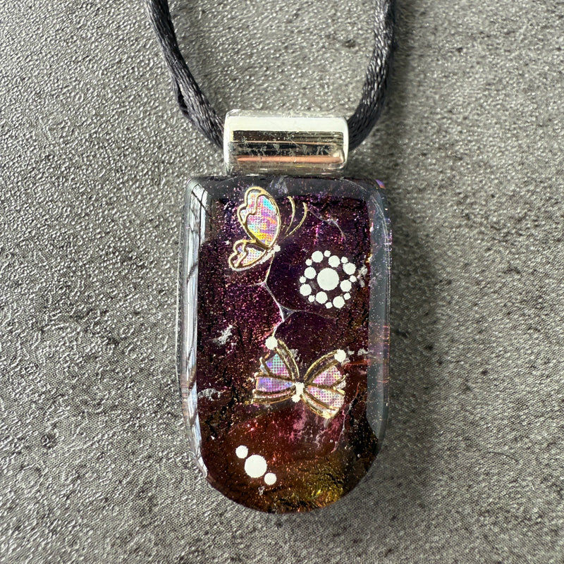 Glass pendant with butterfly design on a gray surface