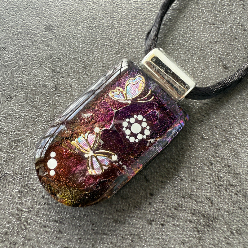 Decorative pendant with butterfly designs on a textured surface