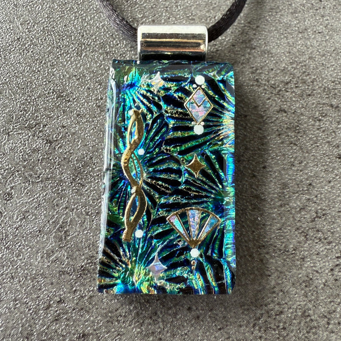 Decorative pendant with tropical leaf pattern on a gray surface