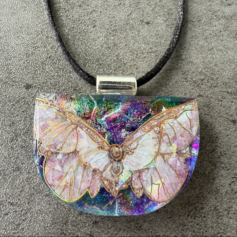 Butterfly-shaped pendant on a cord against a gray background