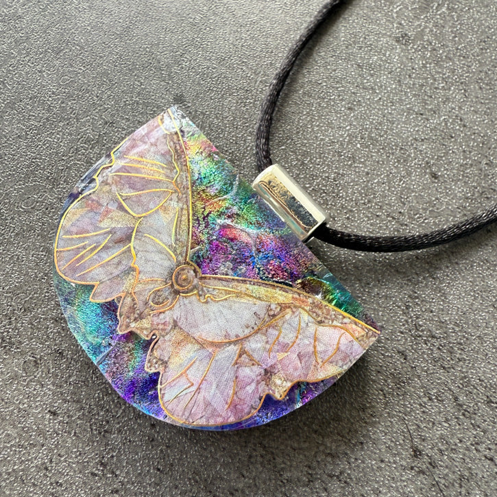 Butterfly pendant on a cord against a gray background