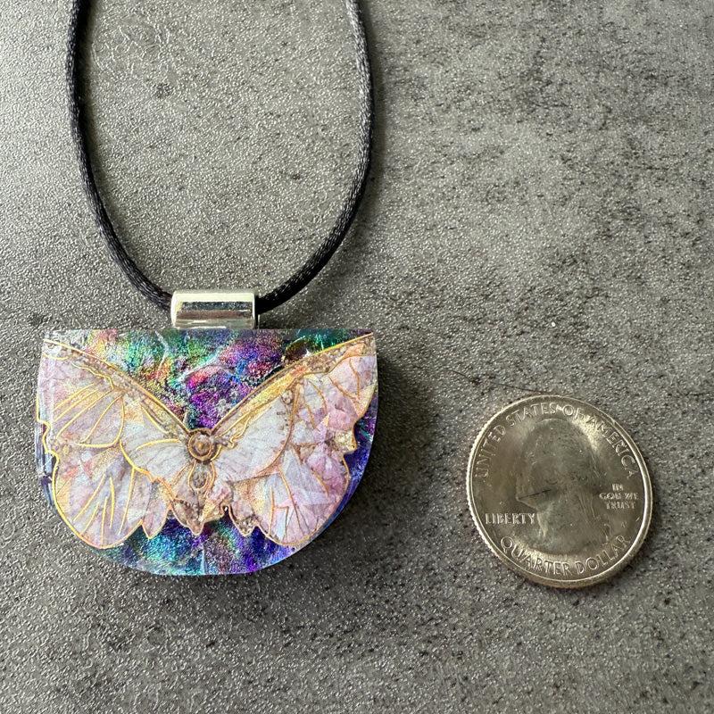 Butterfly pendant necklace on a gray surface with a penny for scale