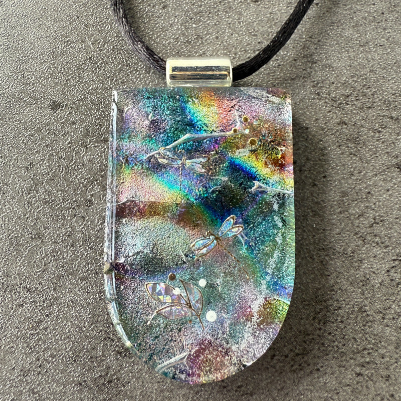 Multicolored pendant with dragonfly design on a gray surface
