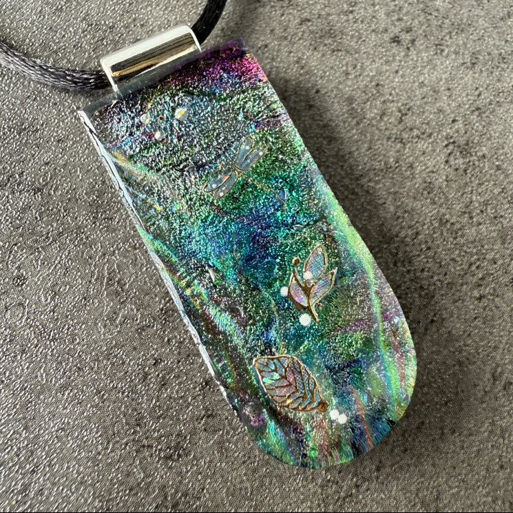 Multicolored pendant with fish designs on a textured surface