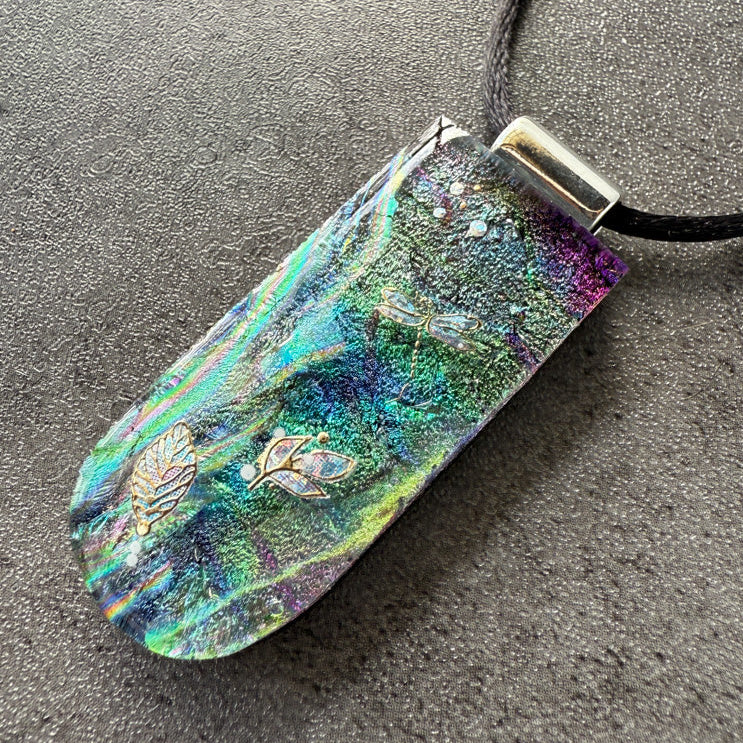 Iridescent pendant with floral designs on a dark surface
